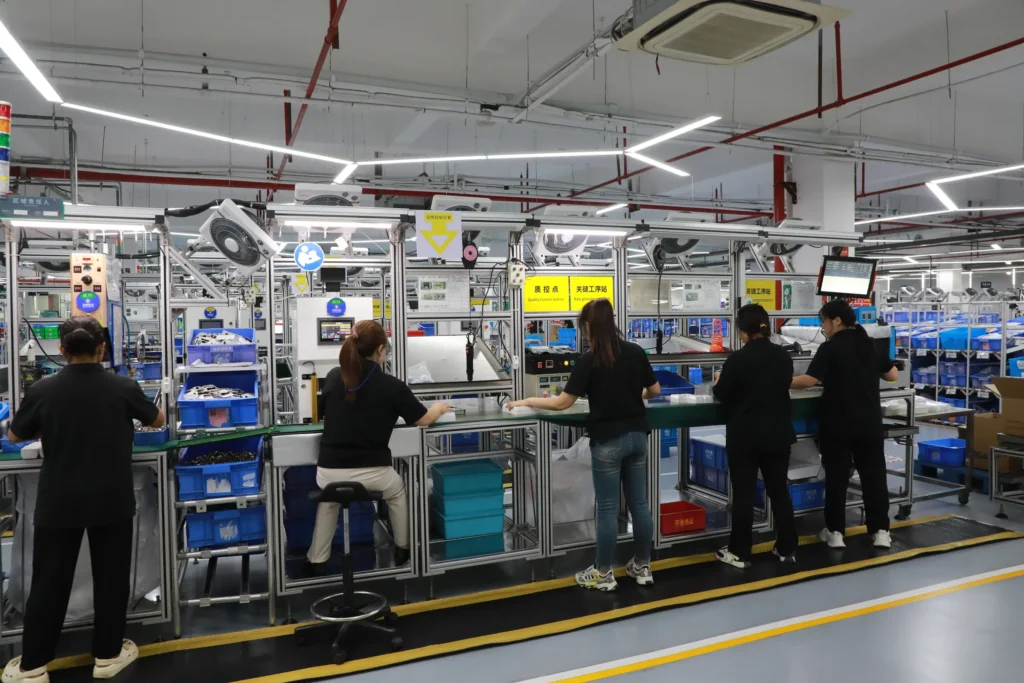Wide view of an assembly line with an in-line quality control and key process station, five workers at the bench