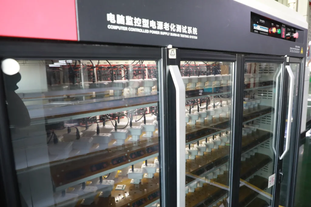 Rows of electrical socket products undergoing burn-in testing inside a computer-controlled power supply ageing test cabinet