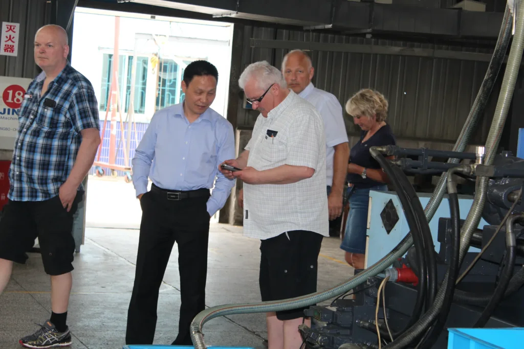 European visitors touring the injection moulding floor with Etman staff, overhead crane and machines in the background