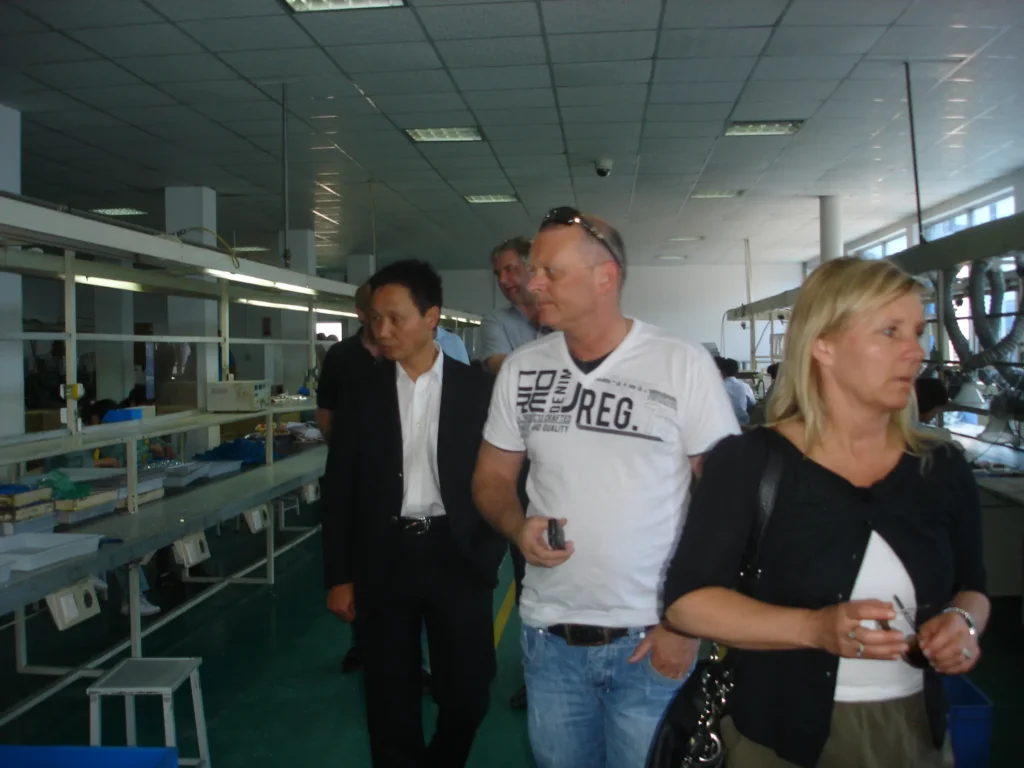 Visitors and an Etman staff member reviewing an injection moulding machine control panel together