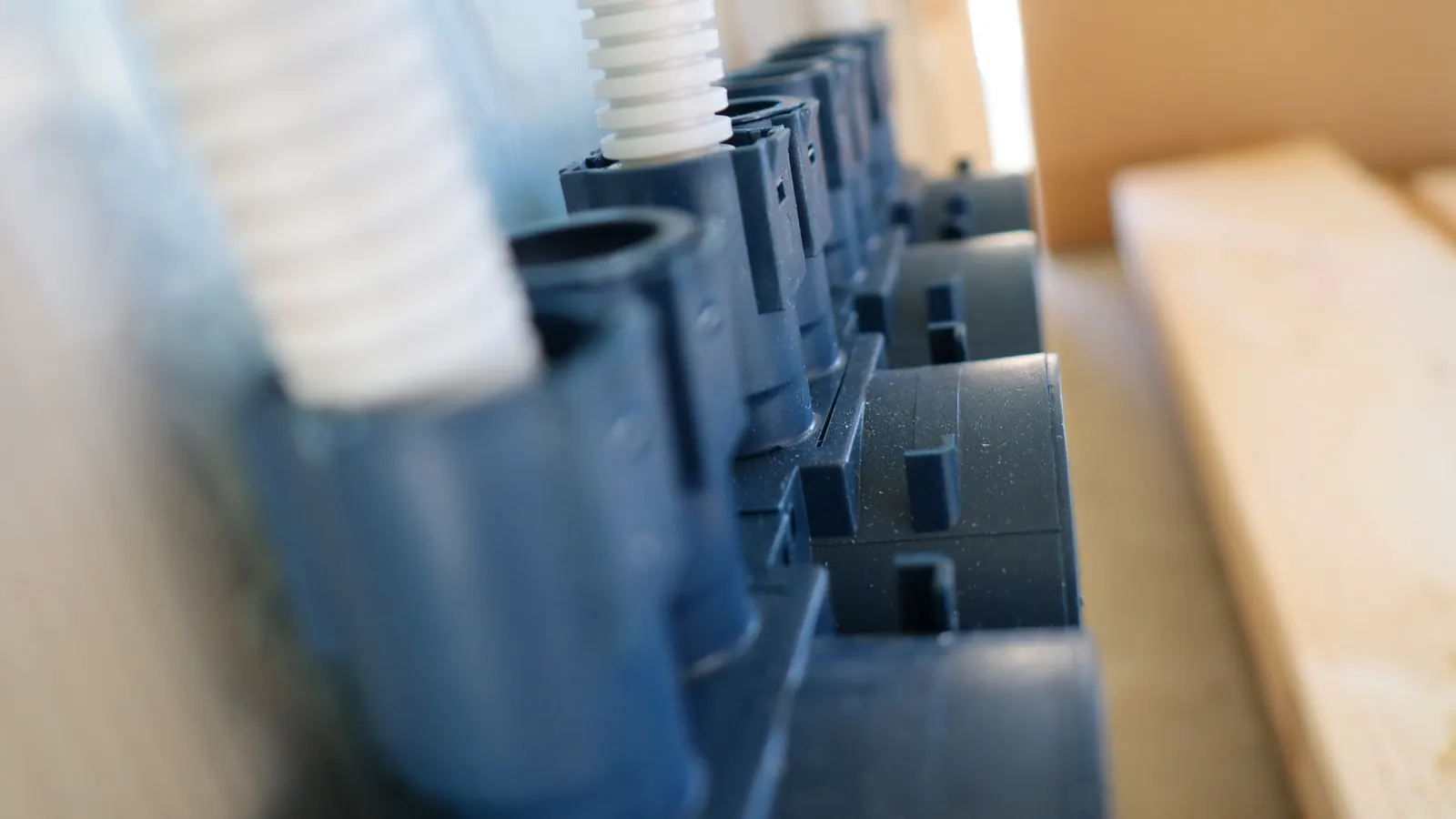 Row of blue installation boxes with conduits, photographed along the wall before boarding