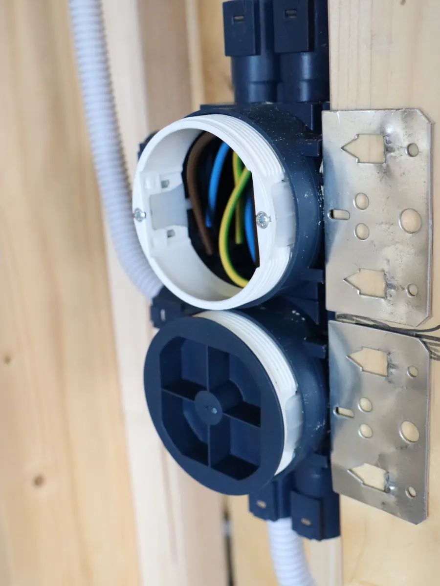 Two blue installation boxes stacked on a timber stud and fixed with a steel bracket, conduits connected above and below