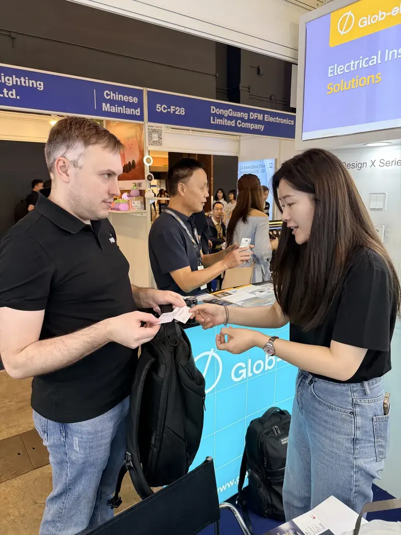 Glob-el team member handing a business card to a visitor at the Hong Kong Lighting Fair