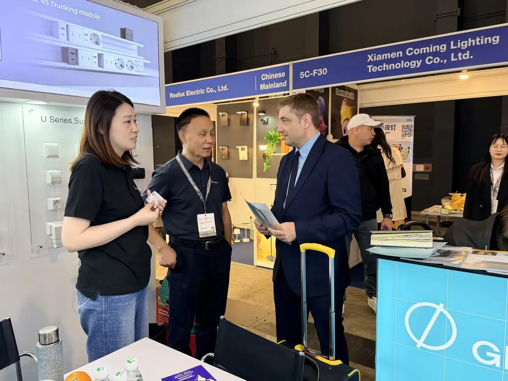 Glob-el representative talking with visitors in the aisle at the Hong Kong Lighting Fair