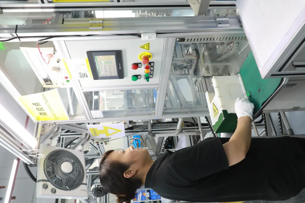 A Quality Control Station sign above electrical safety test equipment, with an operator checking a component