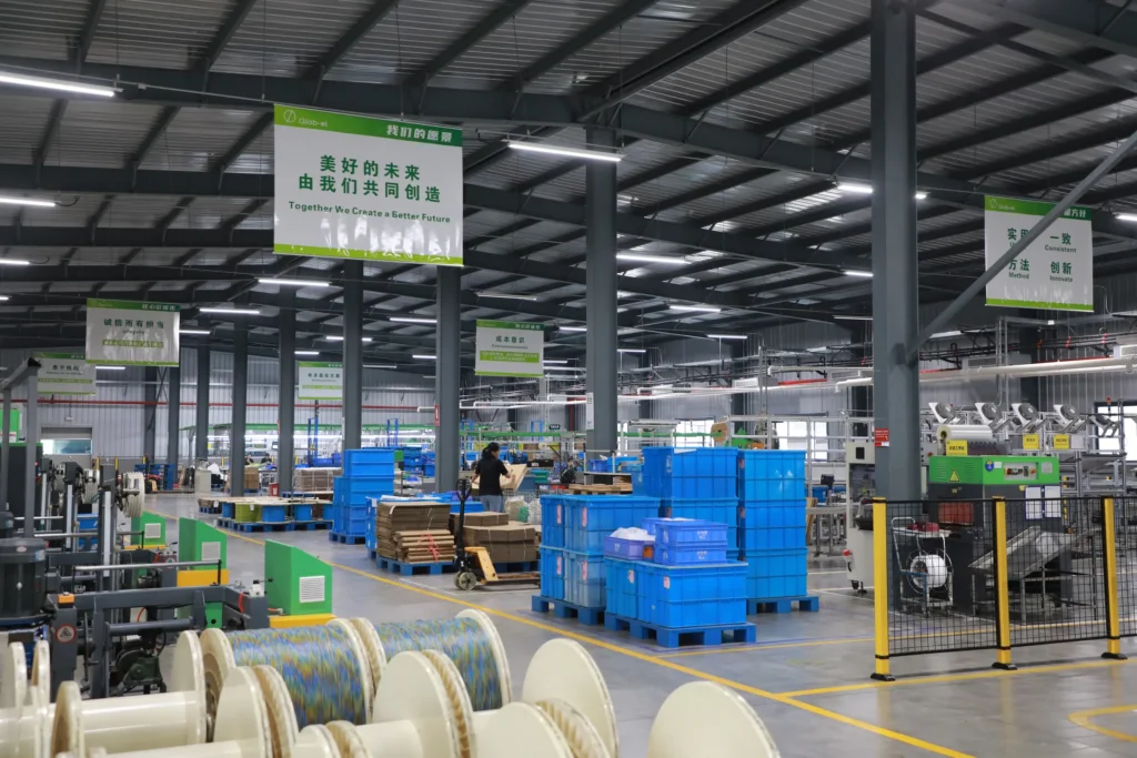 Wire and cable winding line at the Changzhou factory, with finished cable spools staged next to company vision and values banners